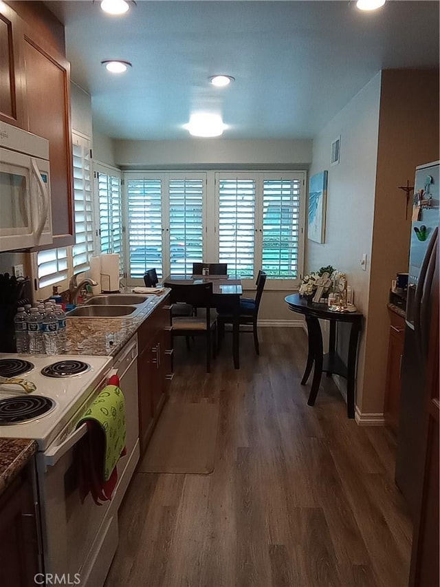 kitchen with dark wood-type flooring, stone counters, sink, and stainless steel appliances