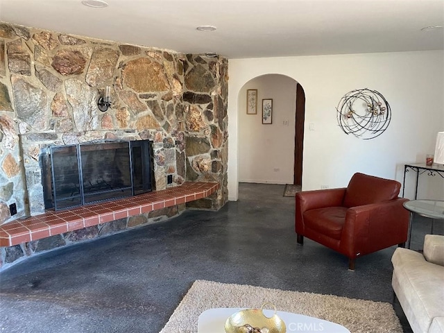 living area with a fireplace and arched walkways