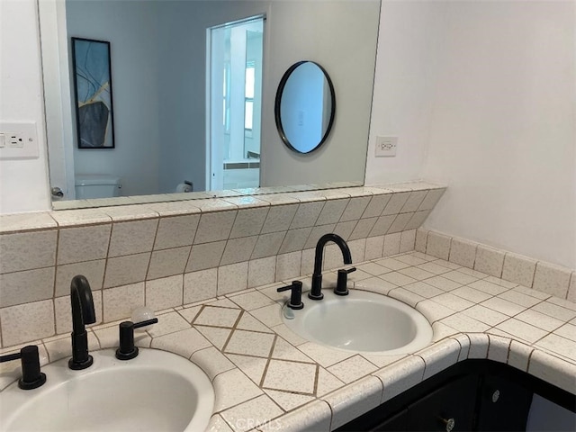 bathroom with vanity, toilet, and tasteful backsplash