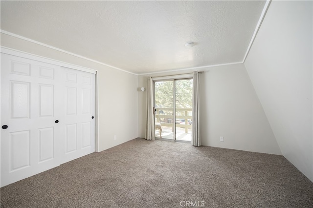 unfurnished bedroom with lofted ceiling, a closet, carpet flooring, and a textured ceiling