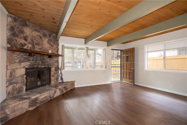 unfurnished living room featuring a healthy amount of sunlight, a stone fireplace, dark hardwood / wood-style flooring, and beamed ceiling