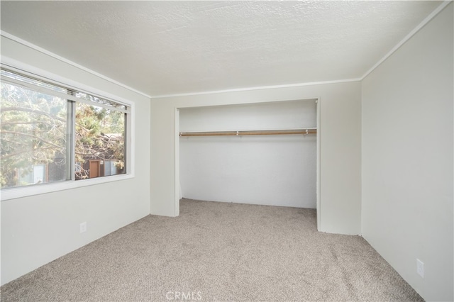 unfurnished bedroom featuring light carpet, a textured ceiling, a closet, and crown molding