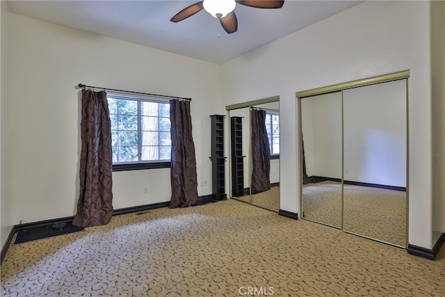 unfurnished bedroom featuring carpet floors, two closets, and ceiling fan