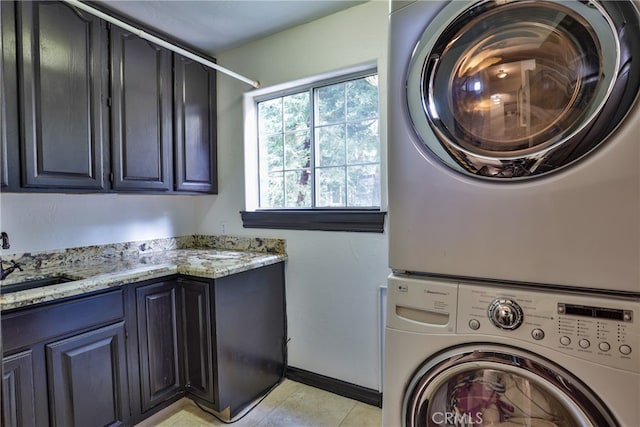 laundry room with sink, stacked washing maching and dryer, cabinets, and light tile patterned floors