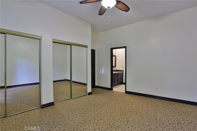 unfurnished bedroom featuring ceiling fan, multiple closets, and ensuite bath