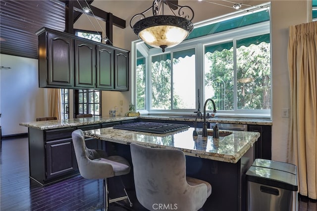 kitchen featuring a kitchen bar, a kitchen island, light stone counters, and dark hardwood / wood-style floors