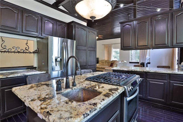 24048 Altdorf Dr, Crestline, CA 92325 - kitchen with stainless steel appliances, light stone countertops, dark brown cabinetry, an island with sink, and open floor plan