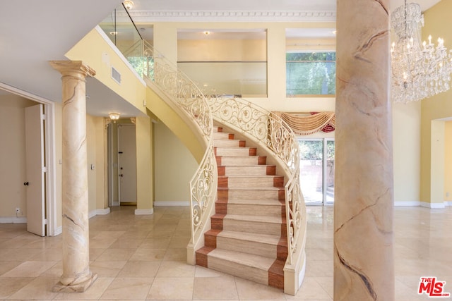 stairs featuring a notable chandelier, tile patterned flooring, a high ceiling, and ornate columns