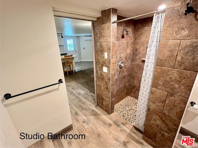 bathroom featuring hardwood / wood-style flooring, an AC wall unit, and a shower with shower curtain