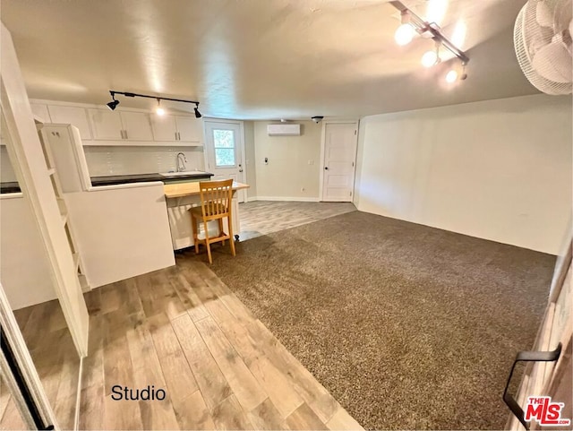 interior space featuring sink, a wall unit AC, white cabinets, hardwood / wood-style flooring, and track lighting