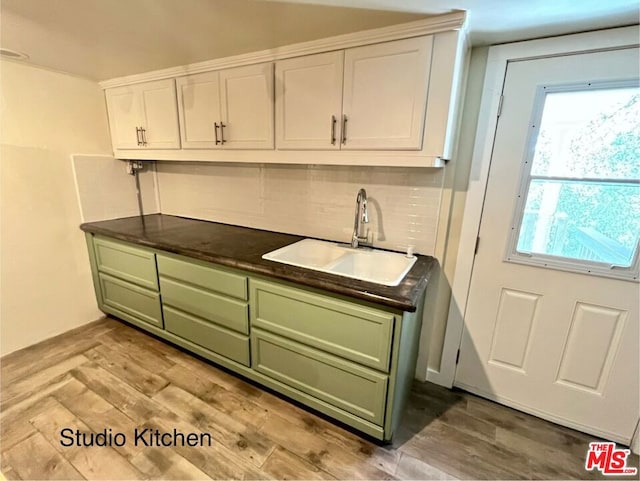 kitchen featuring tasteful backsplash, sink, green cabinets, light hardwood / wood-style floors, and white cabinets