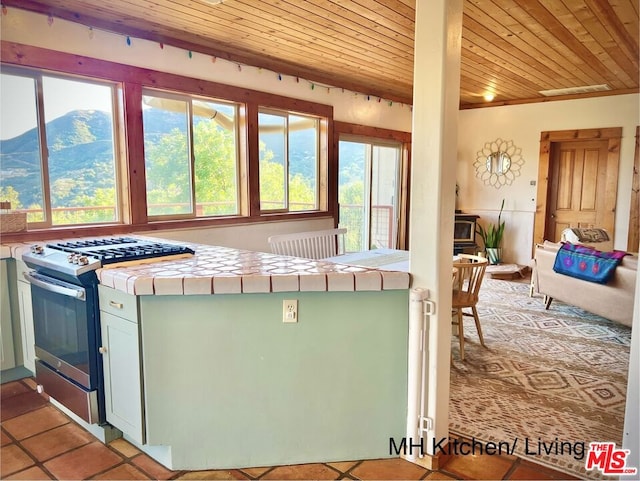 kitchen featuring a mountain view, a wealth of natural light, tile counters, and stainless steel gas range oven