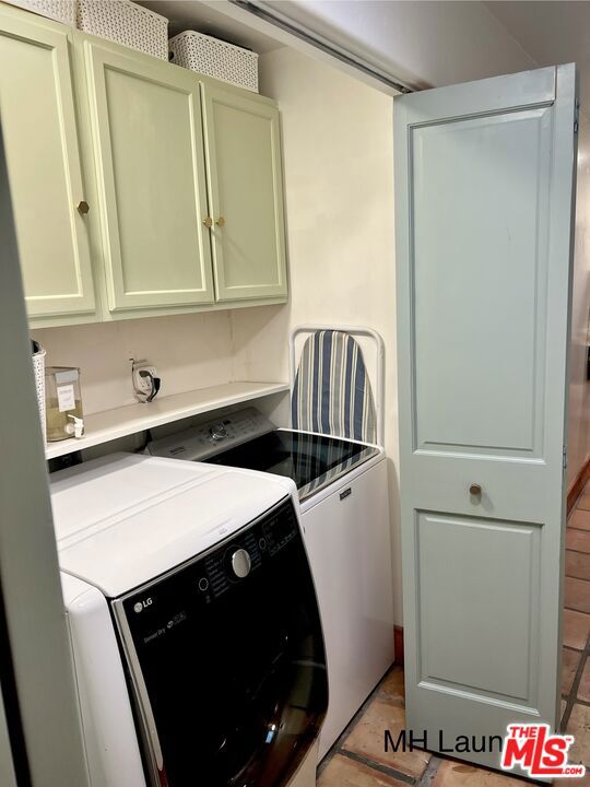 clothes washing area featuring cabinets and separate washer and dryer