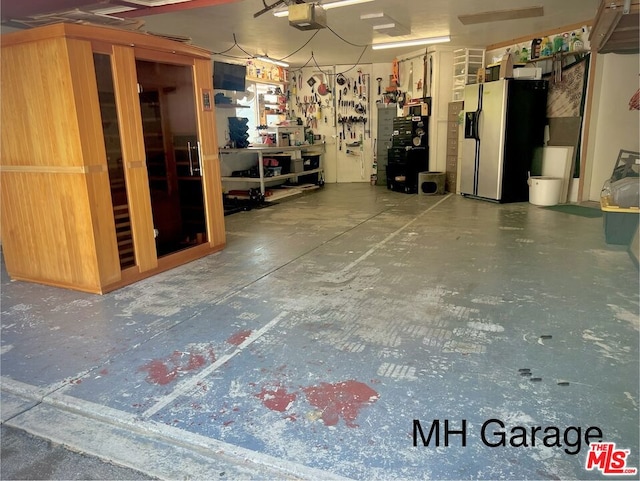 garage with a garage door opener and stainless steel fridge