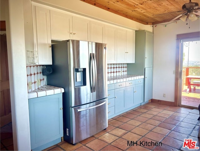 kitchen with tile countertops, stainless steel refrigerator with ice dispenser, wooden ceiling, white cabinetry, and ceiling fan