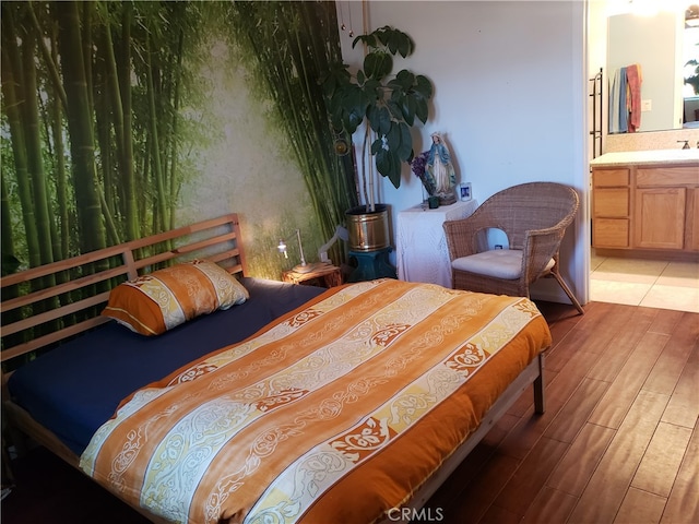 bedroom featuring light wood-type flooring, connected bathroom, and sink