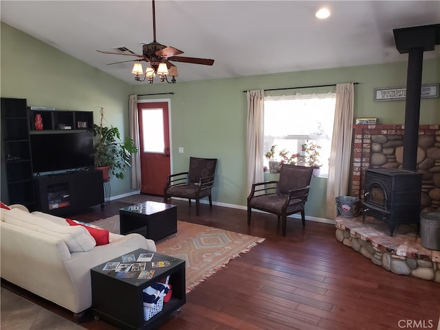 living room featuring lofted ceiling, dark wood-type flooring, ceiling fan, and a wood stove