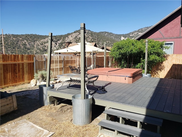 deck with a mountain view and a covered hot tub