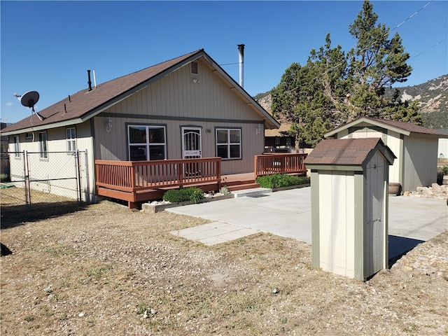 view of front of property featuring a shed, a patio, and a wooden deck