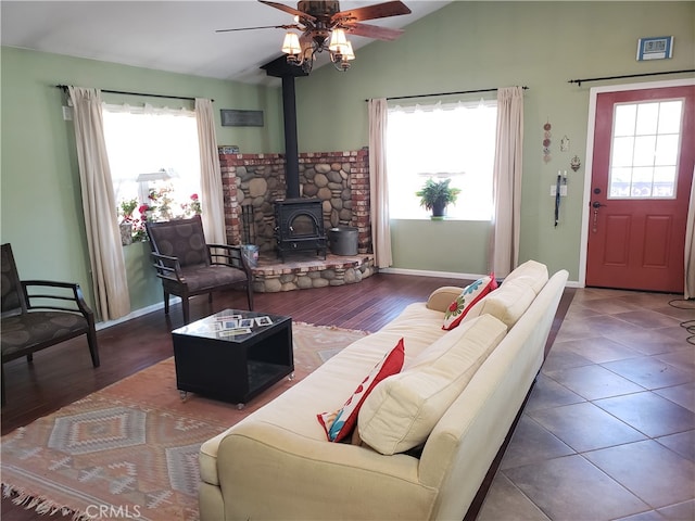 living room with a wood stove, vaulted ceiling, ceiling fan, and hardwood / wood-style flooring