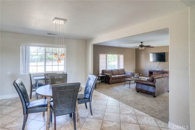 dining area featuring a textured ceiling, ceiling fan, and light colored carpet