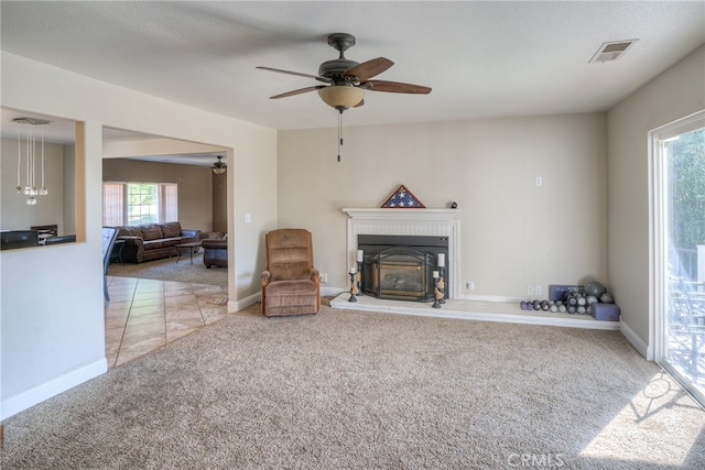 living room featuring light carpet, a textured ceiling, ceiling fan, and a healthy amount of sunlight