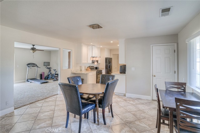 dining area with ceiling fan and light colored carpet