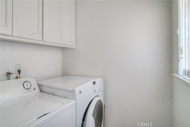 clothes washing area with cabinets and washing machine and clothes dryer