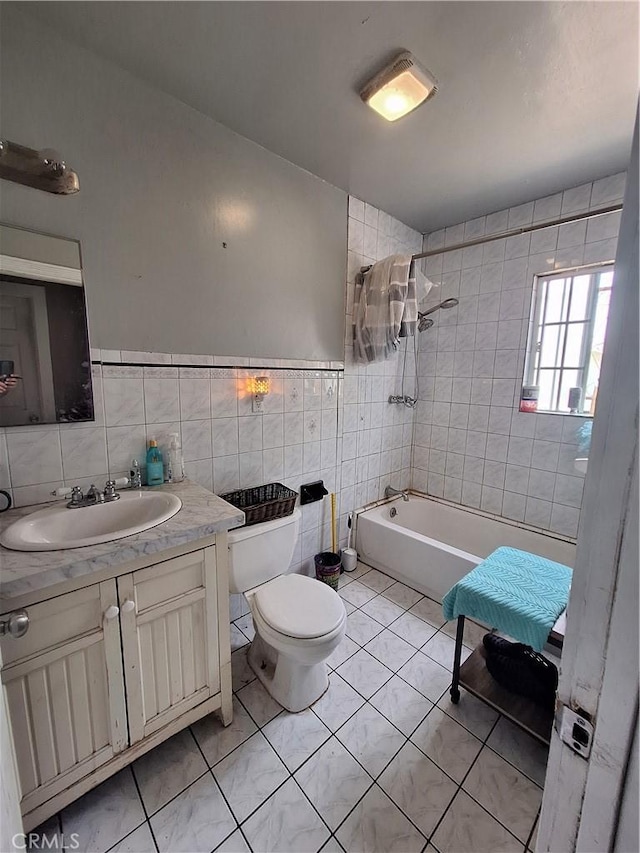 full bathroom with tile walls, tiled shower / bath combo, vanity, toilet, and tile patterned floors