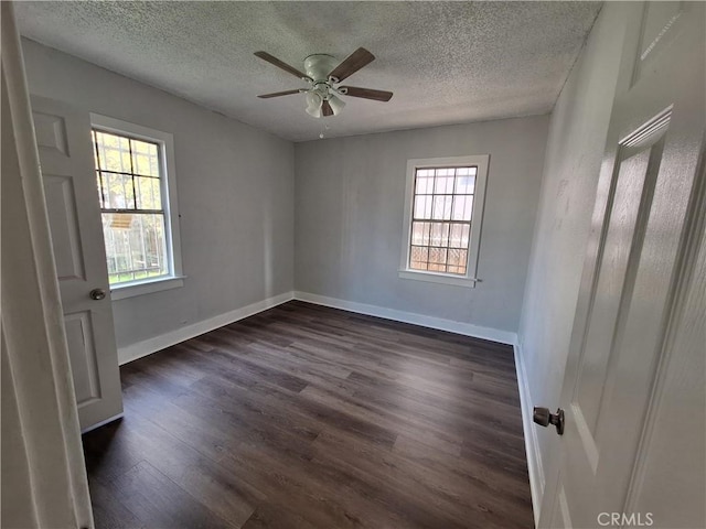 unfurnished bedroom with dark wood-type flooring, ceiling fan, multiple windows, and a textured ceiling