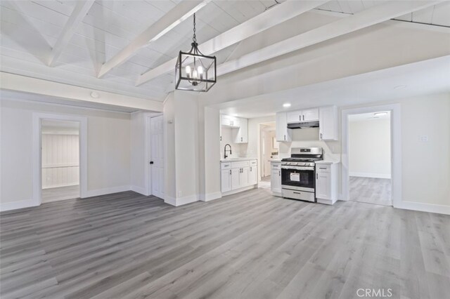 kitchen with white cabinetry, stainless steel range, sink, decorative light fixtures, and light wood-type flooring