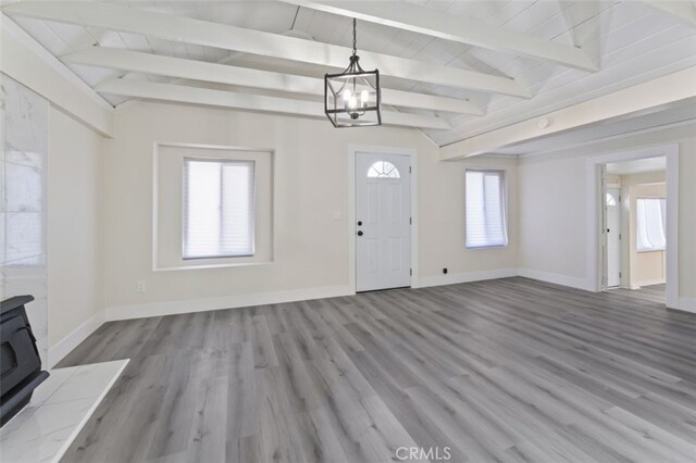 foyer with a wood stove, wooden ceiling, lofted ceiling with beams, a notable chandelier, and wood-type flooring