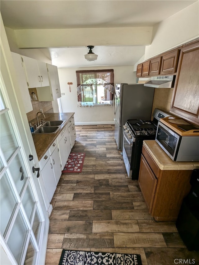 kitchen with beamed ceiling, dark wood-type flooring, sink, stainless steel appliances, and backsplash