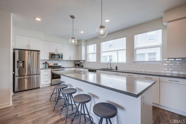 kitchen with stainless steel appliances, white cabinetry, a center island, and plenty of natural light