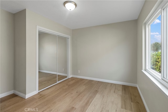 unfurnished bedroom with a closet and light hardwood / wood-style floors