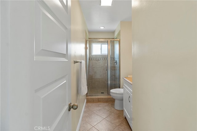 bathroom with toilet, vanity, tile patterned floors, and a shower with door