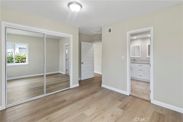 unfurnished bedroom featuring light hardwood / wood-style flooring, a closet, and connected bathroom