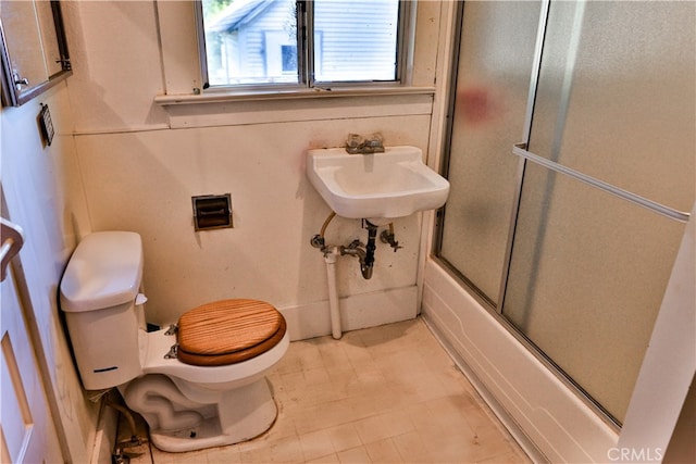 full bathroom featuring toilet, sink, and bath / shower combo with glass door