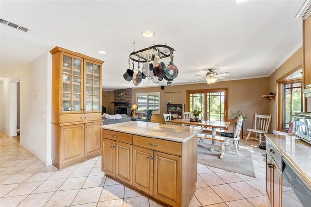 kitchen with ornamental molding, light tile patterned flooring, a brick fireplace, light stone counters, and ceiling fan