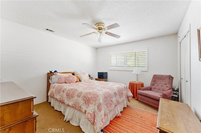 carpeted bedroom featuring a closet, a textured ceiling, and ceiling fan