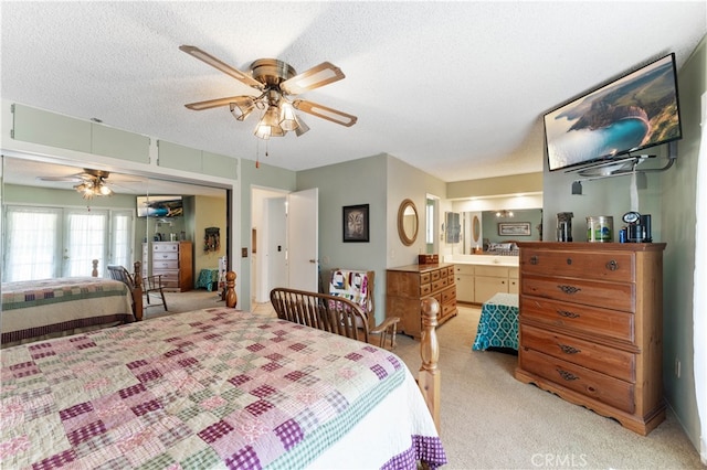 carpeted bedroom featuring a closet, ceiling fan, a textured ceiling, and ensuite bath