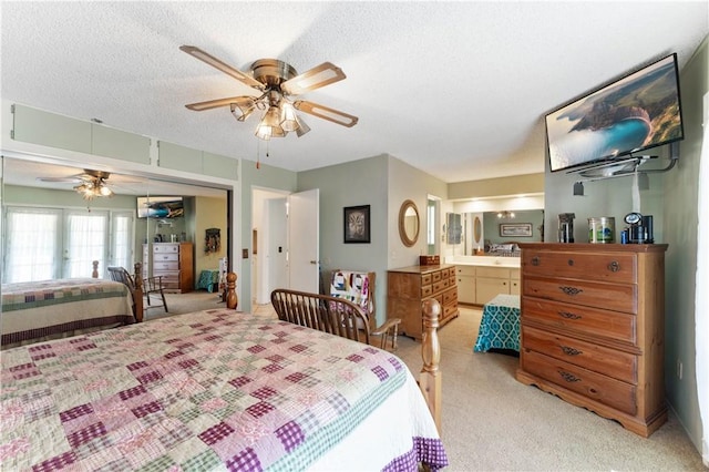 bedroom with a textured ceiling, ensuite bath, a ceiling fan, and light colored carpet