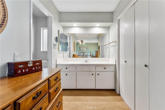 ensuite bathroom with a textured ceiling, ensuite bath, vanity, and a ceiling fan