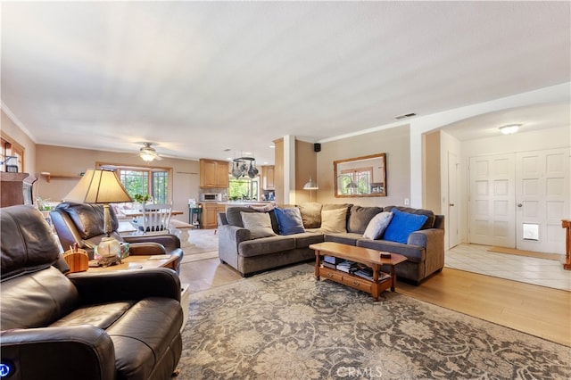 living room with crown molding, light hardwood / wood-style flooring, and ceiling fan