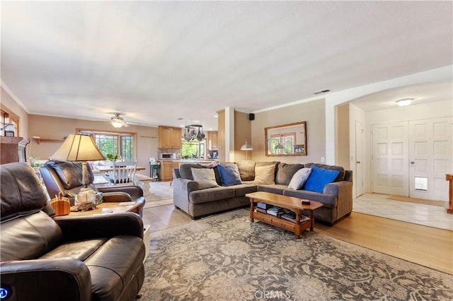 living room with light wood-type flooring, visible vents, and crown molding