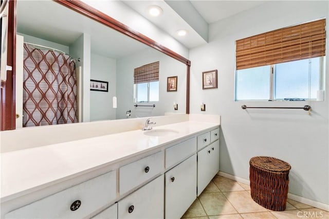 bathroom with a wealth of natural light, vanity, baseboards, and tile patterned floors