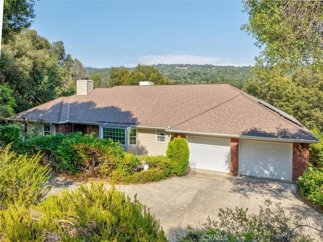 39309 Forest Park Ln, Oakhurst, CA 93644 - single story home with a chimney, driveway, brick siding, and a garage
