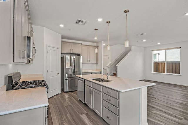 kitchen featuring pendant lighting, gray cabinets, dark wood-type flooring, sink, and appliances with stainless steel finishes