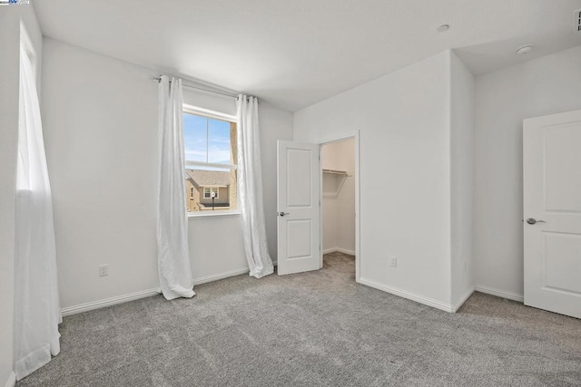 unfurnished bedroom with light carpet, a closet, and a spacious closet