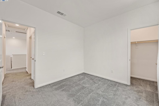 unfurnished bedroom featuring light colored carpet, a closet, and a walk in closet